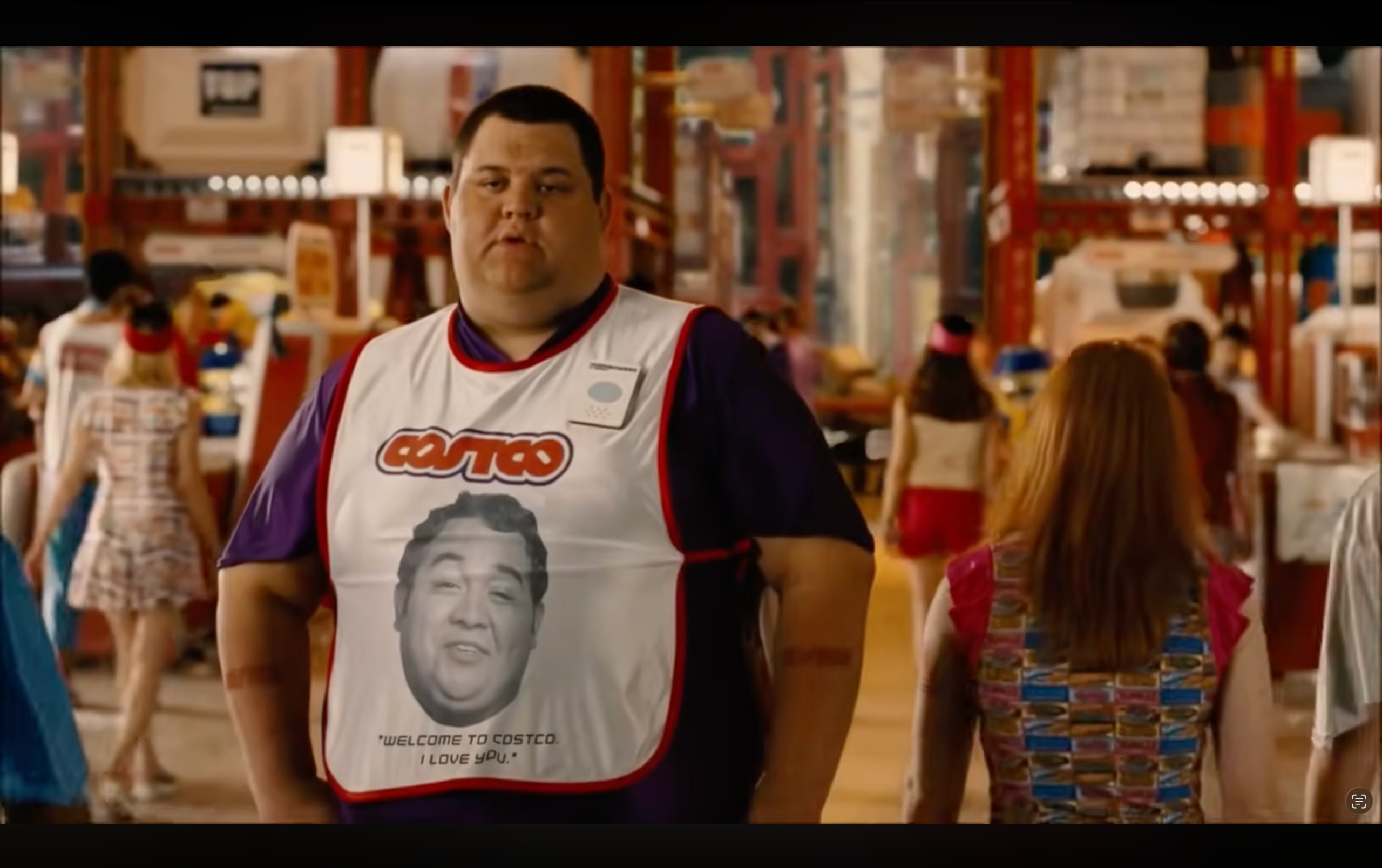 A Costco greeter in Idiocracy wearing a “Welcome To Costco, I Love You” apron.