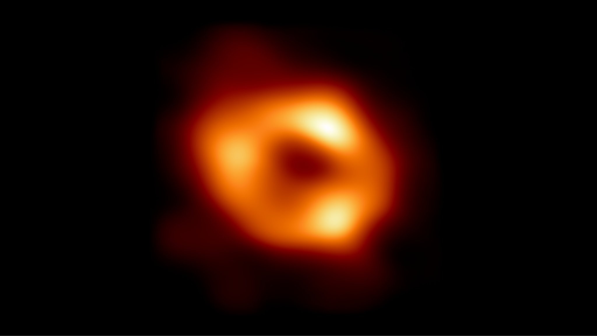 The glowing orange ring of Sagittarius A star, the black hole at the center of the Milky Way, against black space.